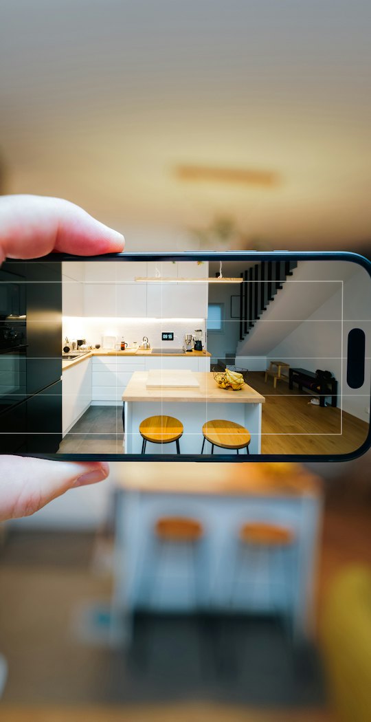 Phone held up filming a bright kitchen for a listing video