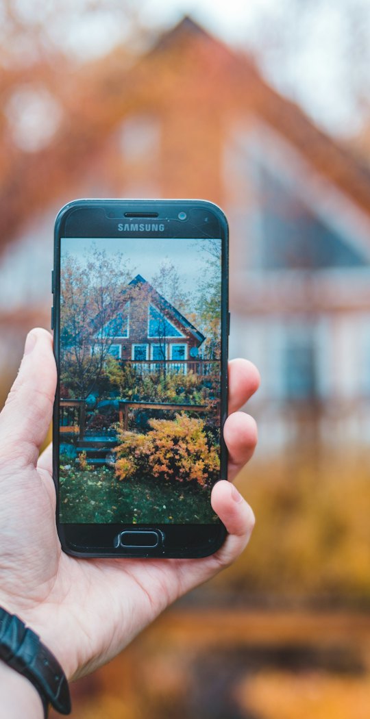 Hand holding up a phone that frames a house